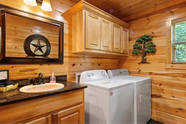 Laundry area with a sink, washing machine and clothes dryer, wooden walls, and wooden ceiling | Image 21