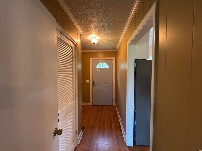 Doorway featuring ornamental molding, a textured ceiling, and hardwood / wood-style flooring | Image 9