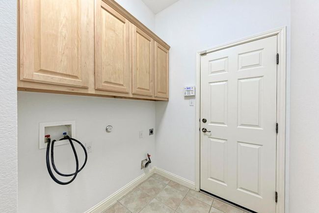 Washroom with hookup for a washing machine, light tile patterned flooring, hookup for a gas dryer, baseboards, and cabinet space | Image 31