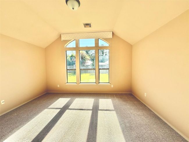Bright, spacious main bedroom room with vaulted ceiling and large windows, offering plenty of natural light and a view of the backyard. | Image 14