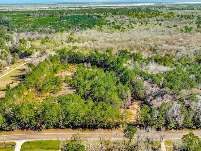 This aerial photo showcases a large, wooded lot with dense greenery, offering privacy and natural surroundings. It features a road access at the front, making it convenient for development or a secluded home site. Ideal for nature lovers seeking tranquility. | Image 6