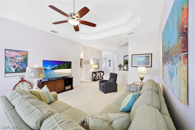 Living room with ceiling fan, a tray ceiling, and carpet flooring | Image 6