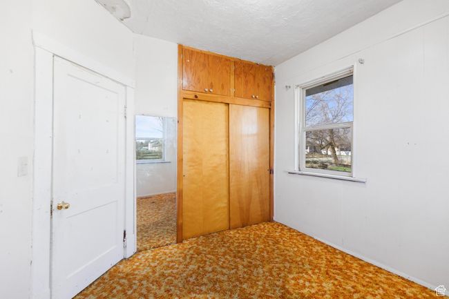 Unfurnished bedroom featuring a closet, a textured ceiling, and carpet | Image 14