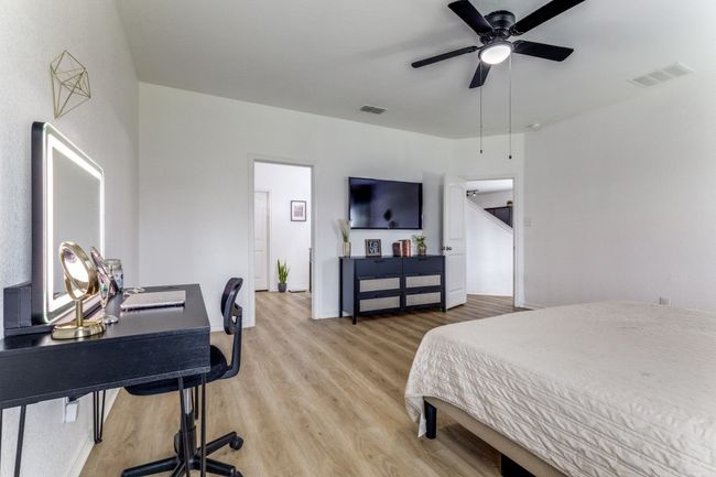 Bedroom featuring light wood-type flooring, an office area, and a ceiling fan | Image 24