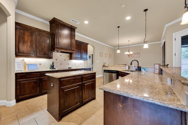 Kitchen featuring dishwasher, a large island with sink, a sink, arched walkways, and tasteful backsplash | Image 8