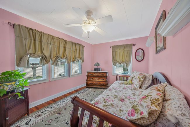 Bedroom with multiple windows, wood finished floors, baseboards, and a ceiling fan | Image 19