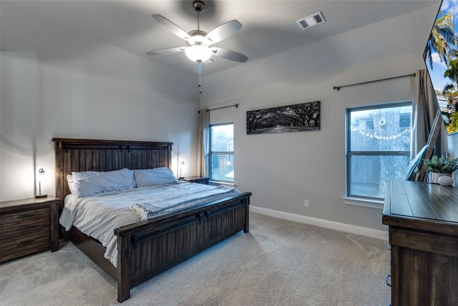Bedroom featuring baseboards, visible vents, light colored carpet, and ceiling fan | Image 14