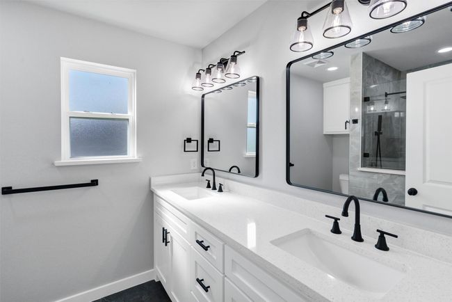 Bathroom with tiled shower, double vanity, baseboards, and toilet | Image 27