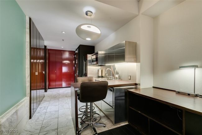 Kitchen with light marble finish floors, modern cabinets, stainless steel microwave, and pendant lighting | Image 25