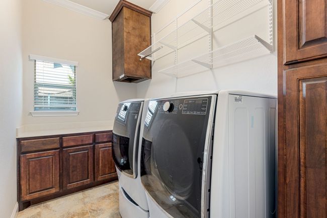 Washroom featuring washing machine and clothes dryer, cabinet space, and crown molding | Image 36