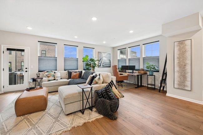 Expansive family room featuring a cozy fireplace and TV area, with a dedicated desk space in the back—versatile layout perfect for relaxing, working, or entertaining, all filled with natural light. | Image 12