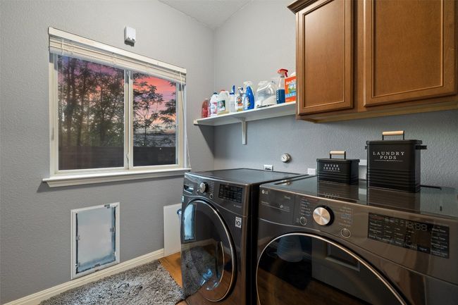 Hall from garage has half bath, walk in pantry and laundry room with medium dog door and large window. | Image 12
