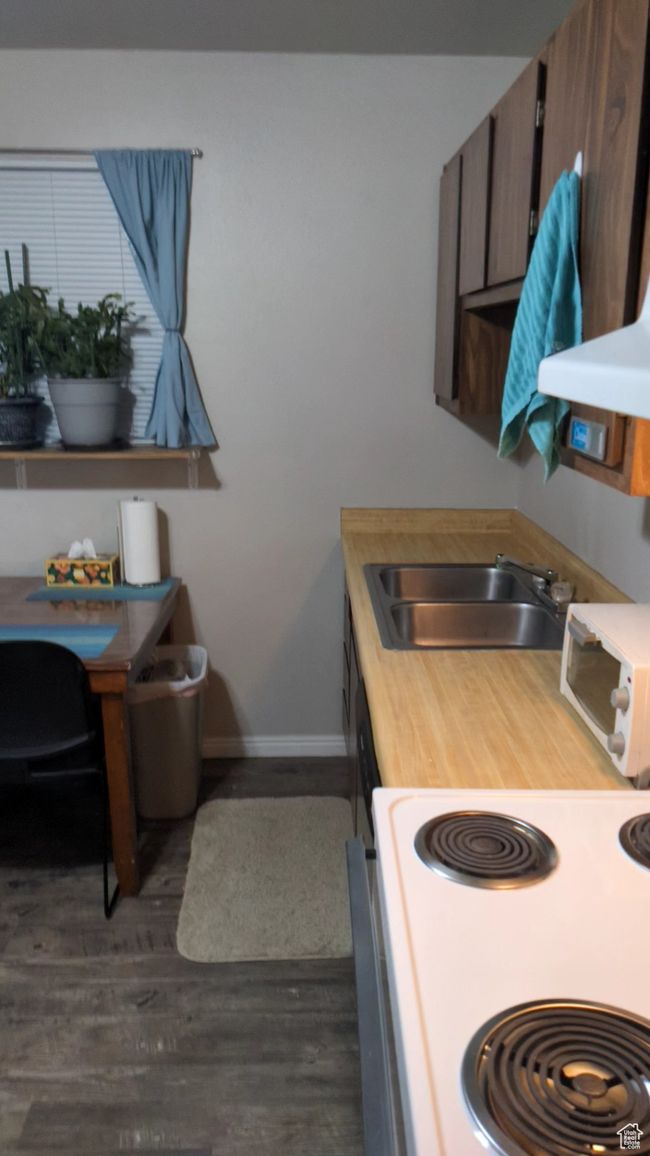 Kitchen featuring electric range, a sink, baseboards, dark wood finished floors, and an office area | Image 9