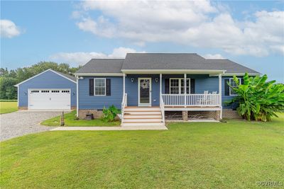 Ranch-style home with a garage, a front yard, and covered porch | Image 1