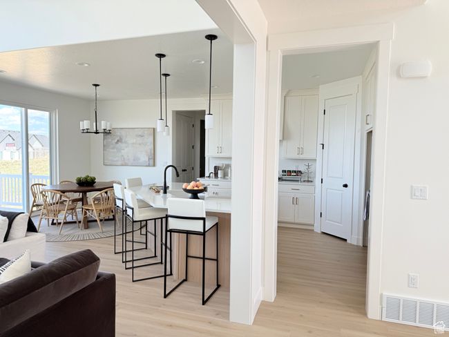 Kitchen with light wood-style flooring, a breakfast bar, white cabinetry, light countertops, and recessed lighting | Image 4