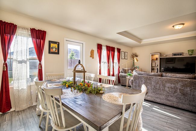 Dining space with wood finished floors, a raised ceiling, and ornamental molding | Image 8
