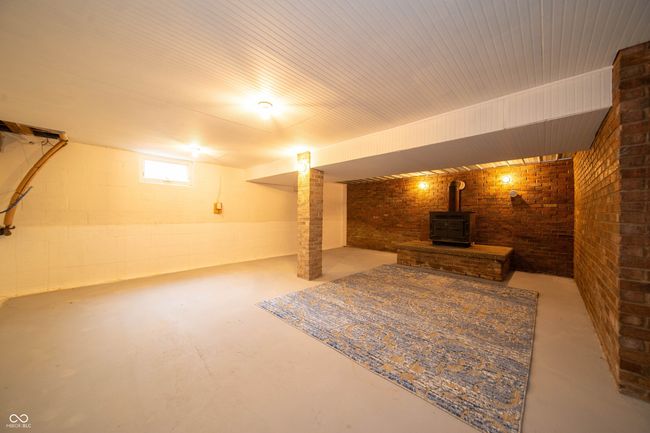 basement featuring a wood stove and brick wall | Image 26