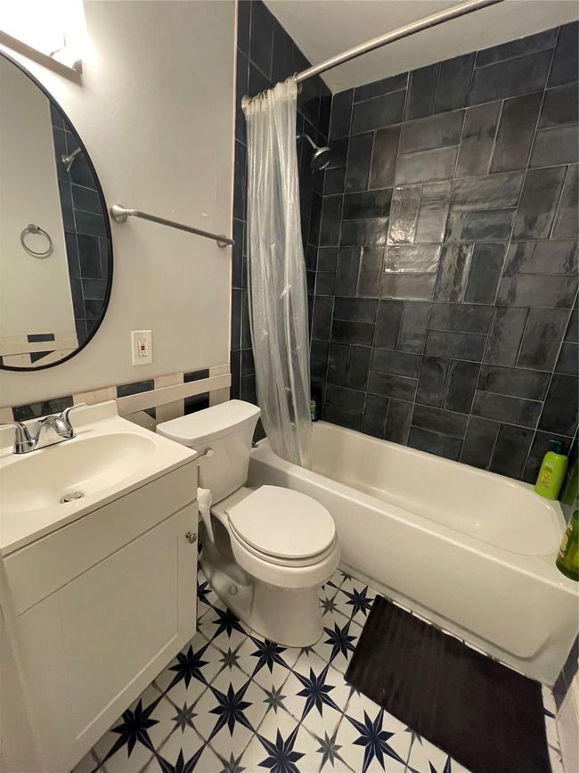 Full bathroom featuring shower / bath combo with shower curtain, vanity, and tile walls | Image 13