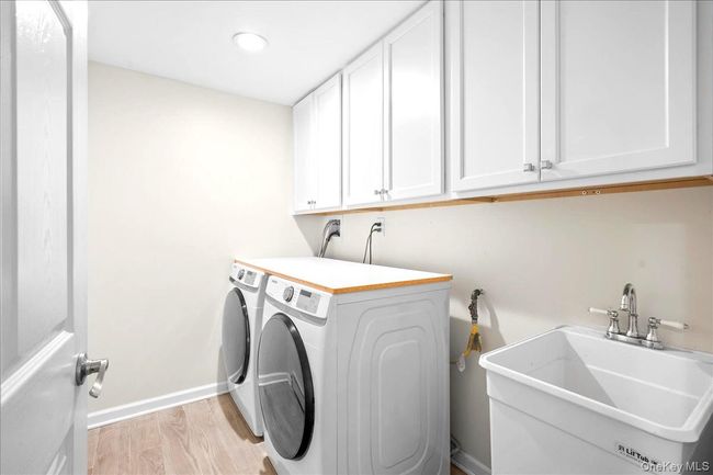 Laundry area with cabinet space, independent washer and dryer, baseboards, light wood-style floors, and recessed lighting | Image 32
