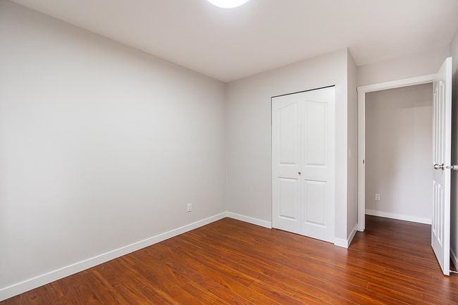 Unfurnished bedroom with dark wood-style floors and a closet | Image 17