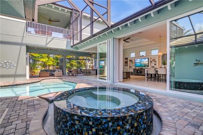 View of pool with an artistic spa attached, an outdoor living space, a lanai, a patio area, and ceiling fan. Note the second floor balcony above. The left side is where the 2nd floor bedroom is located. Right side the Media/Rec Room. | Image 3