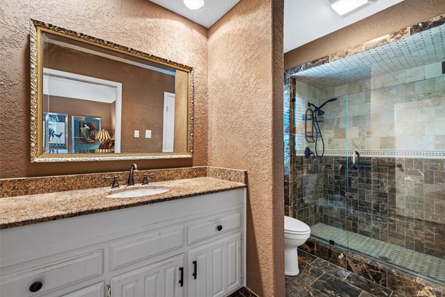 Bathroom with a textured wall, vanity, a shower stall, and toilet | Image 15