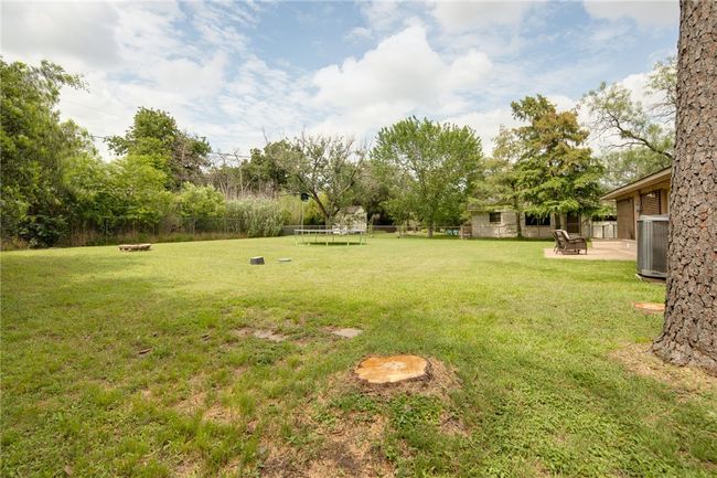 View of yard featuring a trampoline, a fire pit, and cooling unit | Image 21