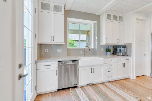 Kitchen with dishwasher, light wood finished floors, beam ceiling, backsplash, and white cabinets | Image 22
