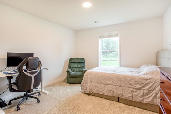 Comfortable bedroom with large window and soft carpet—ideal as a guest suite or home office. | Image 37