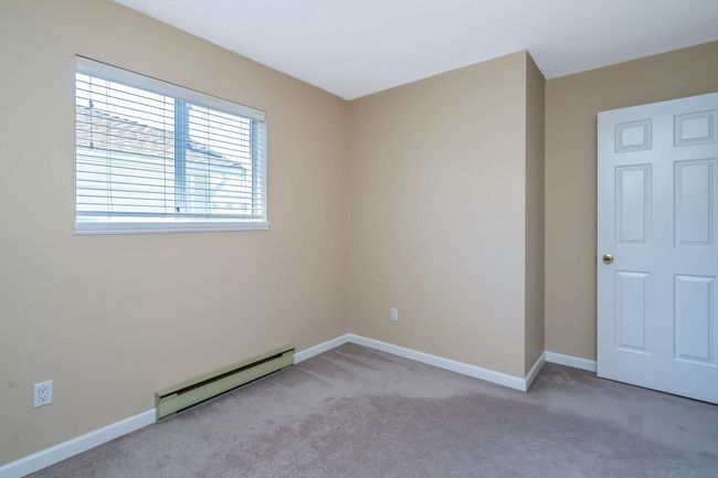 Spare room featuring light carpet, baseboards, and a baseboard heating unit | Image 17