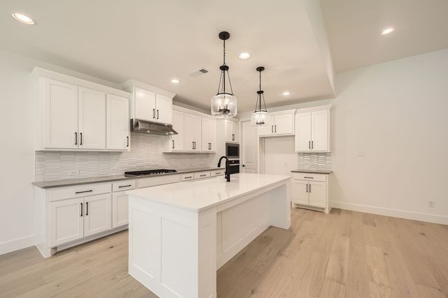 Kitchen featuring appliances with stainless steel finishes, recessed lighting, under cabinet range hood, backsplash, and white cabinets | Image 10