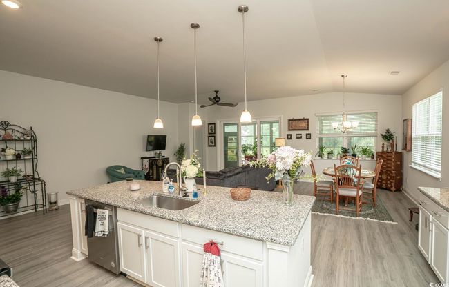 Kitchen with a sink, stainless steel dishwasher, light wood finished floors, white cabinetry, and lofted ceiling | Image 18