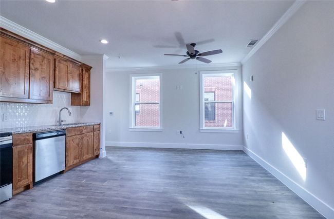 Kitchen featuring dark hardwood / wood-style flooring, decorative backsplash, ceiling fan, stainless steel appliances, and crown molding | Image 6