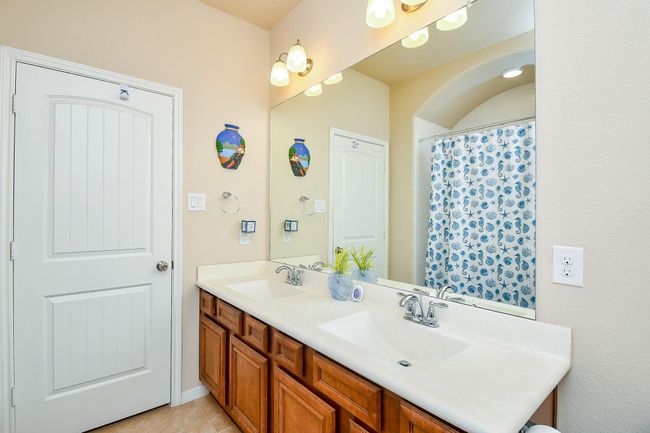 This bathroom features a double sink vanity with wooden cabinets and a large mirror. | Image 25