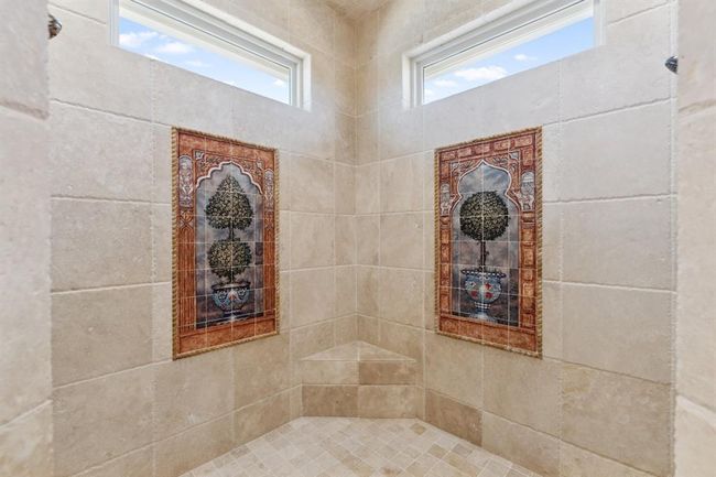 The entire interior of the extra-large shower is crafted of naturaltravertine stone, including the ceiling, the built-in seat, and dual shampoo niches. For added convenience, dualshower heads have been installed. | Image 24