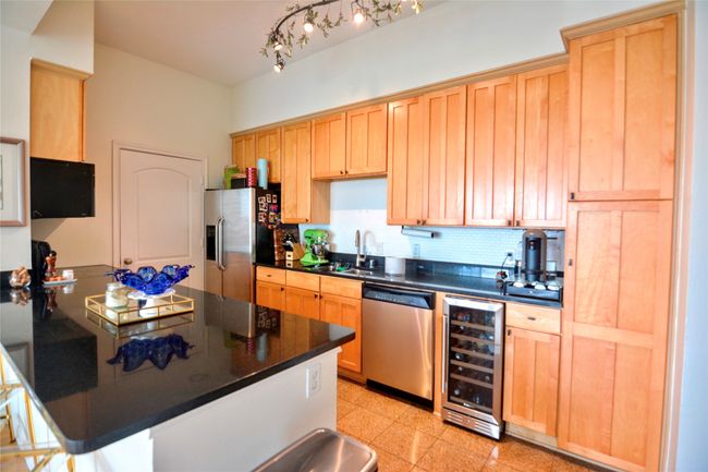 Kitchen with decorative backsplash, wine cooler, stainless steel appliances, light brown cabinets, and a peninsula | Image 33