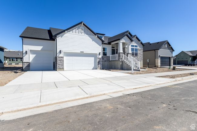 View of front of house featuring board and batten siding, driveway, stone siding, and a garage | Image 4