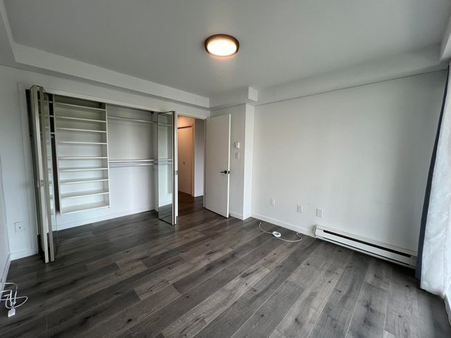 Unfurnished bedroom featuring baseboard heating, dark wood-style flooring, and a closet | Image 22