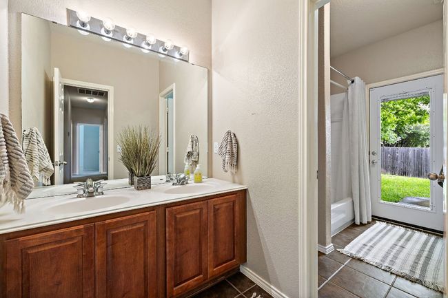 Bathroom featuring double vanity, tile patterned flooring, and shower / tub combo | Image 26