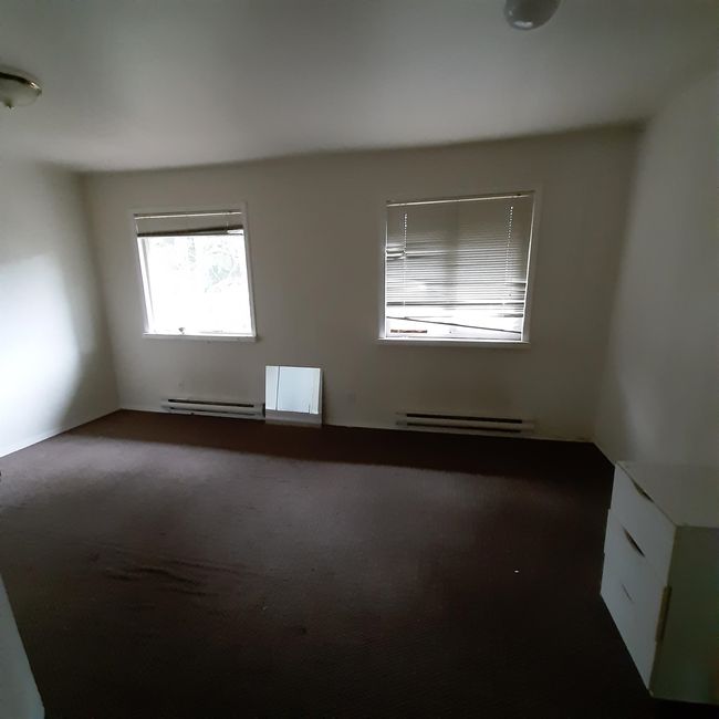 Empty room featuring dark colored carpet, a baseboard heating unit, and baseboard heating | Image 16