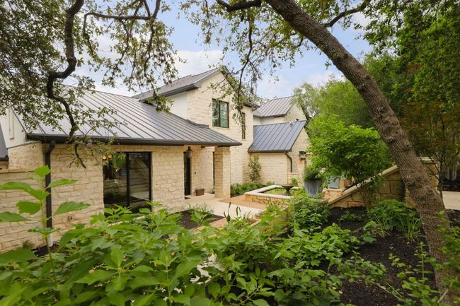 Rear view of property featuring a standing seam roof, a metal roof, stone siding, and a patio area | Image 38