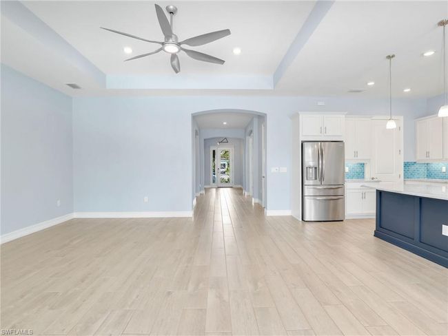 Kitchen with white cabinetry, tasteful backsplash, stainless steel fridge with ice dispenser, light hardwood / wood-style flooring, and decorative light fixtures | Image 14