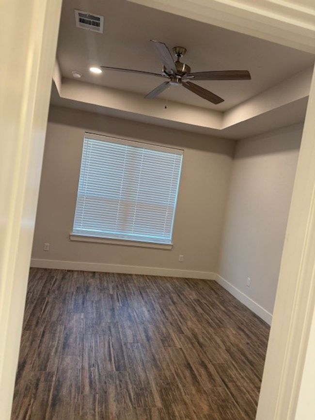 Spare room featuring a raised ceiling, wood finished floors, and a ceiling fan | Image 33