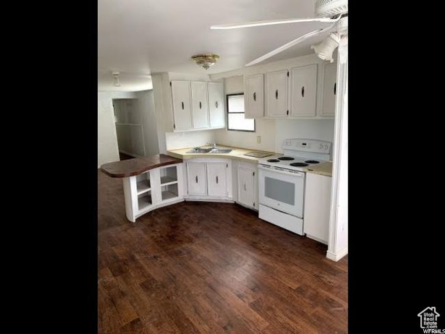 Kitchen with white electric range oven, dark hardwood / wood-style floors, white cabinetry, and sink | Image 40
