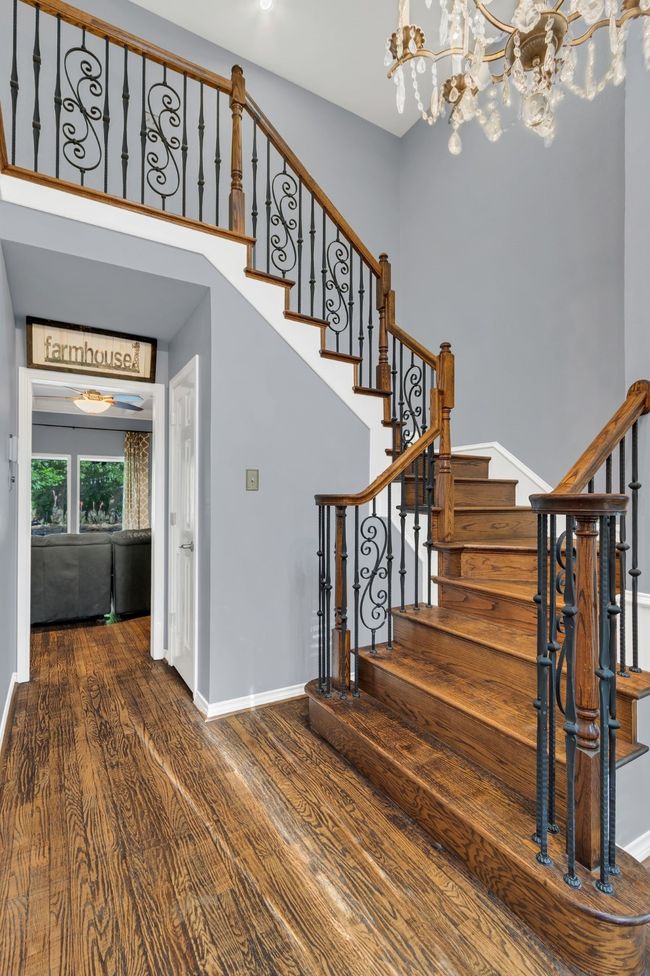 Staircase with wood finished floors and a chandelier | Image 23