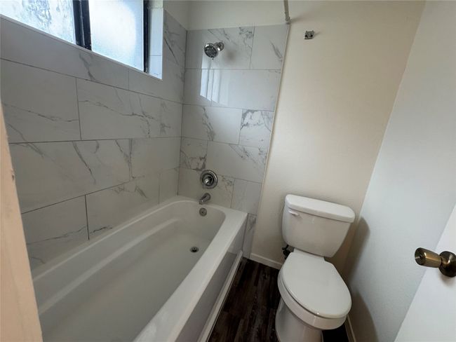 Full bath featuring toilet, wood finished floors, shower / washtub combination, and baseboards | Image 14
