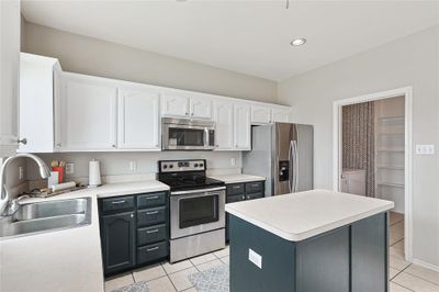 Kitchen featuring stainless steel appliances, white cabinets, sink, a kitchen island, and light tile patterned floors | Image 3