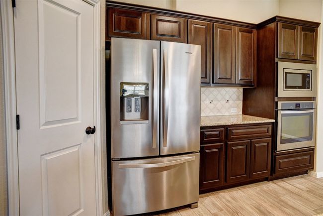 Kitchen featuring appliances with stainless steel finishes, decorative backsplash, light wood-type flooring, and dark brown cabinetry | Image 14