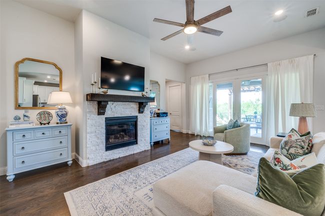 Living room features a gas start fireplace with stone detail and solid wood mantle. Flanked by two nooks for shelving or display for added room. Upgraded lighted ceiling fan and slider doors to the back patio bring this space together. | Image 14