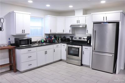 Kitchen with sink, white cabinetry, stainless steel appliances, and light hardwood / wood-style floors | Image 2